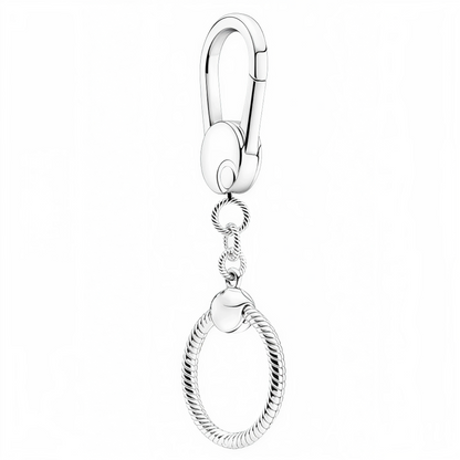 Offrez à vos charms préférés une scène digne d’eux avec ce porte-clé rond en argent 925. Son design torsadé élégant et son système de fixation sécurisé en font l’accessoire parfait pour emporter vos breloques partout, même sans bracelet. Minimaliste mais raffiné, il transforme vos charms en véritable bijou nomade à accrocher à votre trousseau, sac ou trousse.