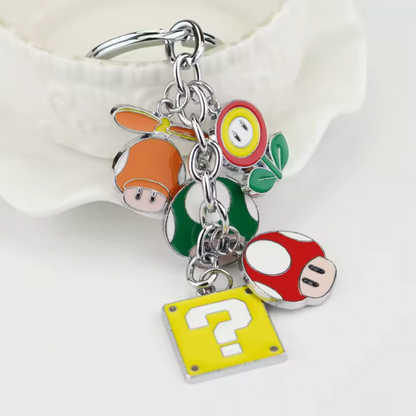 Embarque un morceau du Royaume Champignon avec ce&nbsp;porte-clé en chaîne&nbsp;ultra complet ! Il rassemble&nbsp;5 icônes légendaires&nbsp;de l’univers Mario : le&nbsp;champignon vert 1-Up, le&nbsp;champignon rouge, la&nbsp;fleur de feu, le&nbsp;casque orange à hélice&nbsp;et bien sûr le mythique&nbsp;bloc “?”. Chaque élément est suspendu à une chaîne pour un rendu dynamique et plein de charme. Idéal pour les vrais fans et les nostalgiques du monde pixelisé de Nintendo !